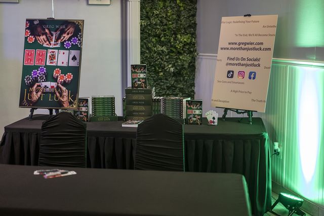 Book release party: Book display table with an easel sign and playing-card art
