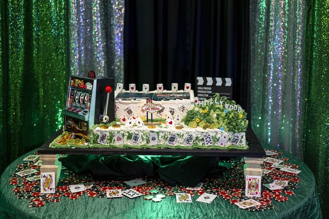 Book release party: Casino-themed cake with a slot machine in front of a green sparkle backdrop