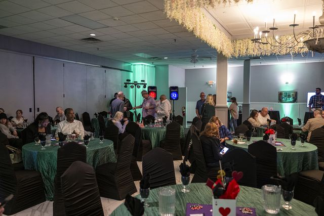 Book release party: A full hall of guests at green-draped tables