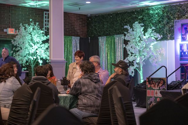 Book release party: Guests at tables near the decorated trees and stage