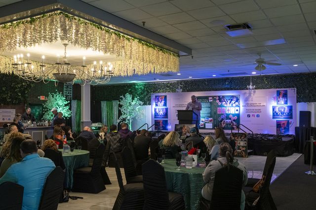 Book release party: The banquet hall under chandeliers, guests at green-draped tables