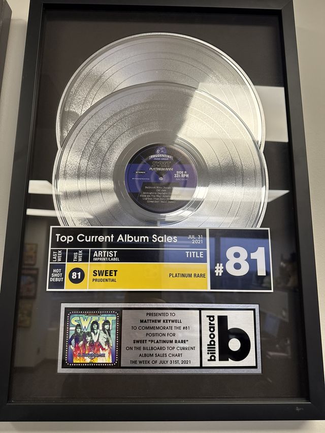 Framed Billboard album sales award with a platinum record