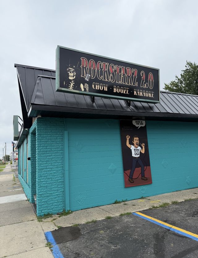 Teal building with a rock-themed sign and mural