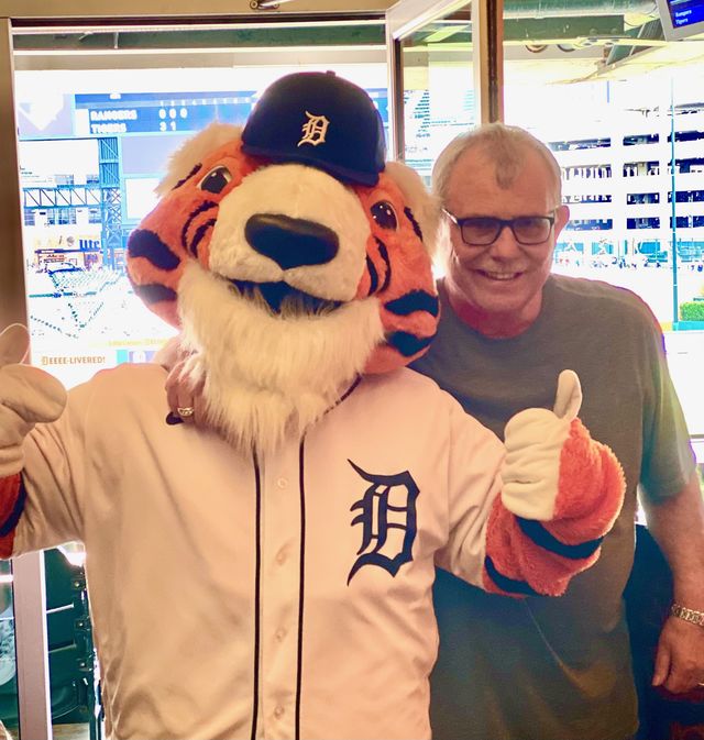 A man giving a thumbs-up beside the Detroit Tigers mascot