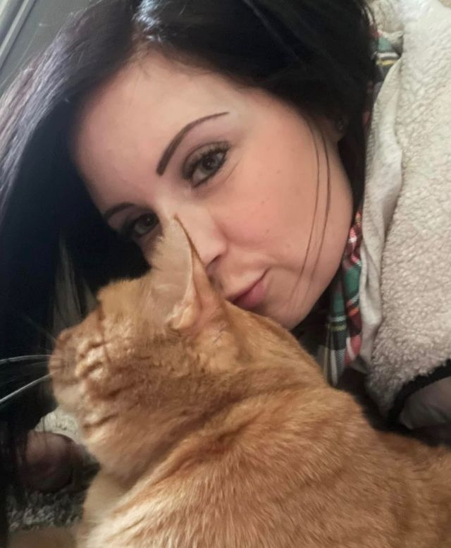 A woman holding an orange cat
