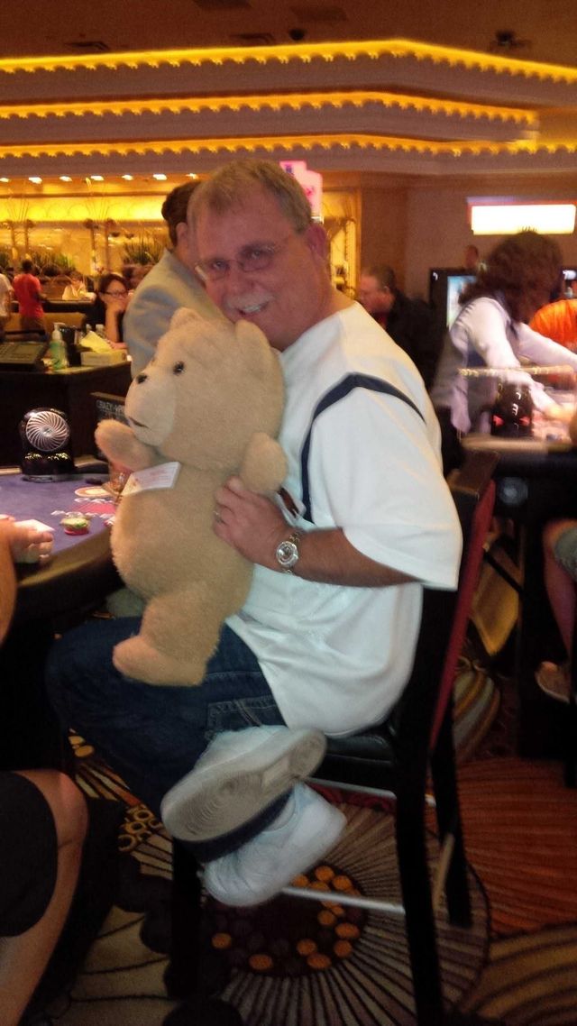 A man holding a large teddy bear in a casino