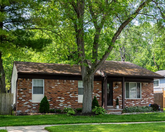 Brick ranch house under trees in summer