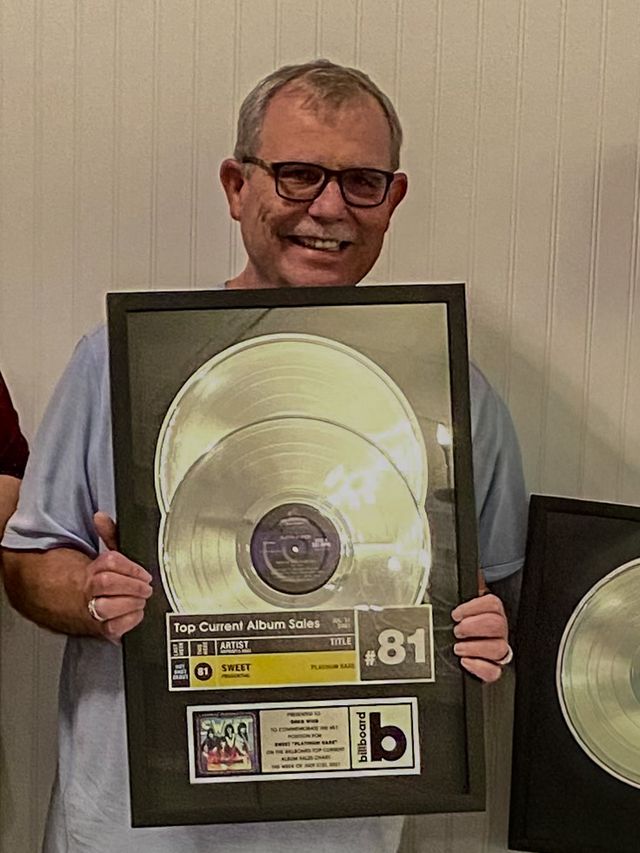 A man holding a framed platinum record award