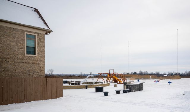 Snowy yard with a play structure beside a house