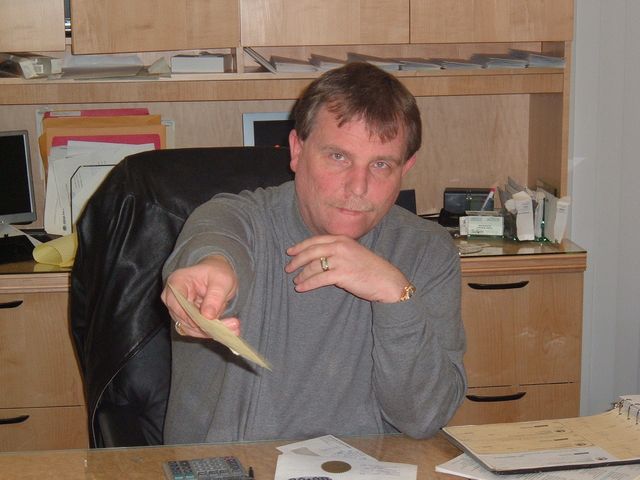 A man at a desk holding out cash
