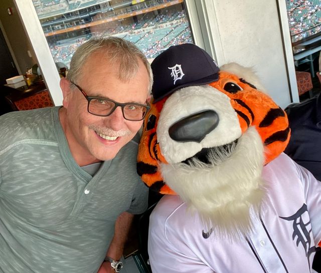 A man with the Detroit Tigers mascot