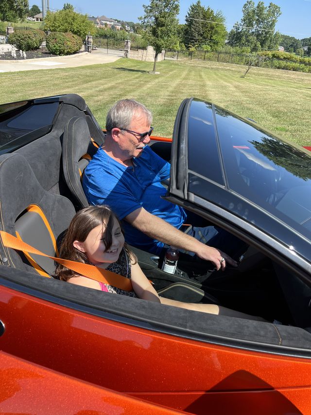 A man and a child in an orange convertible