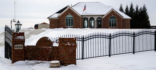 Brick house behind an iron fence in the snow