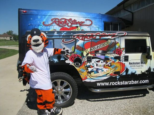 Detroit Tigers mascot beside a decorated Rockstarz Bar vehicle