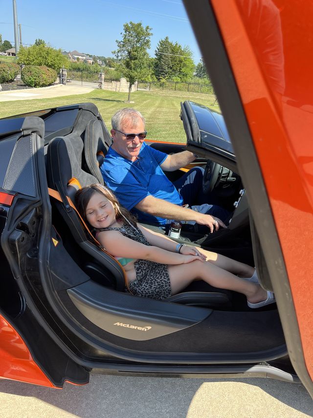 A man and a child in an orange sports car
