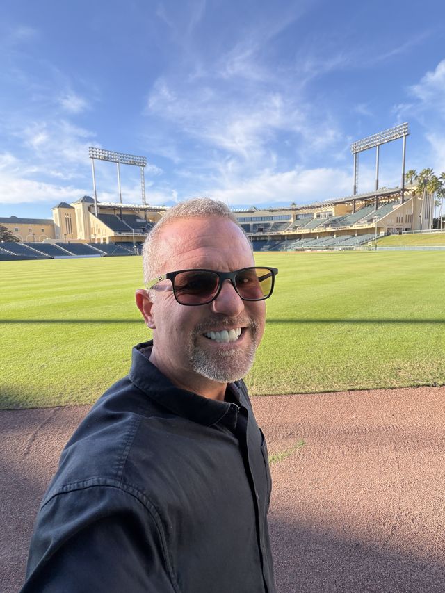 A man in sunglasses at a baseball stadium