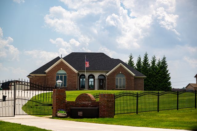Brick house behind an iron fence and gate in summer
